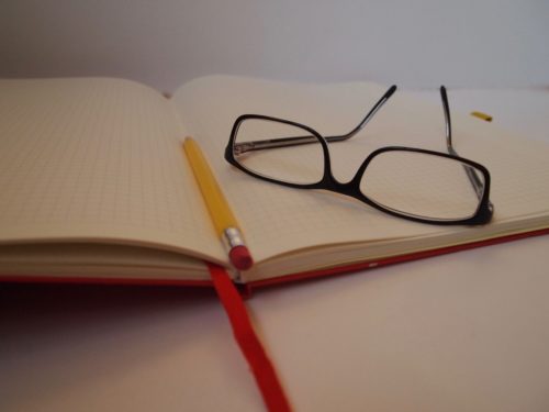 Glasses on open notebook with pencil